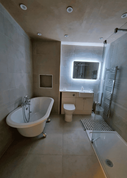 An en-suite with a roll-top slipper bath, floor-mounted mixer, backlit mirror and heated towel rail.